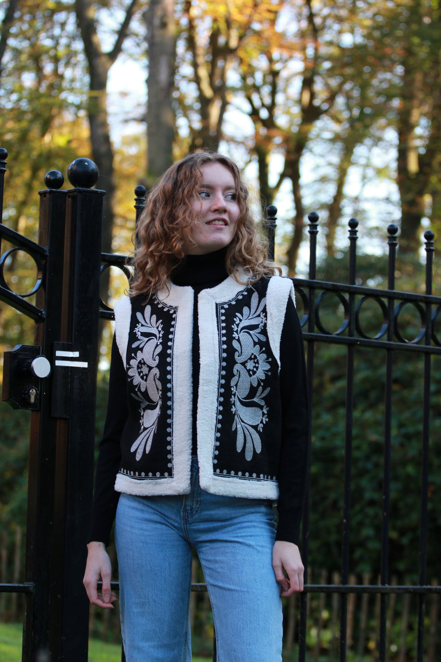 Dames gilet Cloé in zwart met boho borduurwerk, gedragen met zwarte coltrui