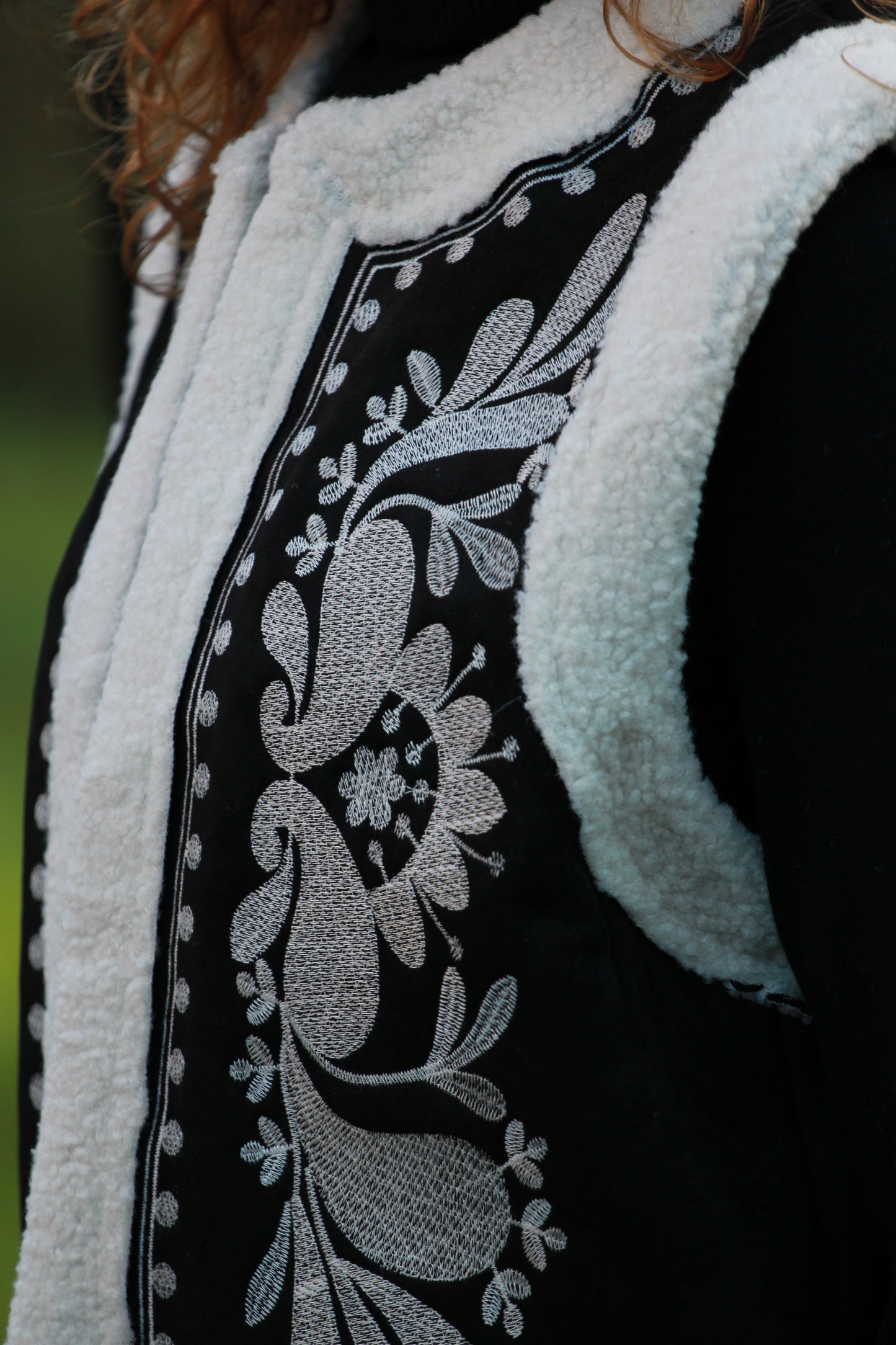 Close-up van witte borduursels op zwart boho gilet Cloé